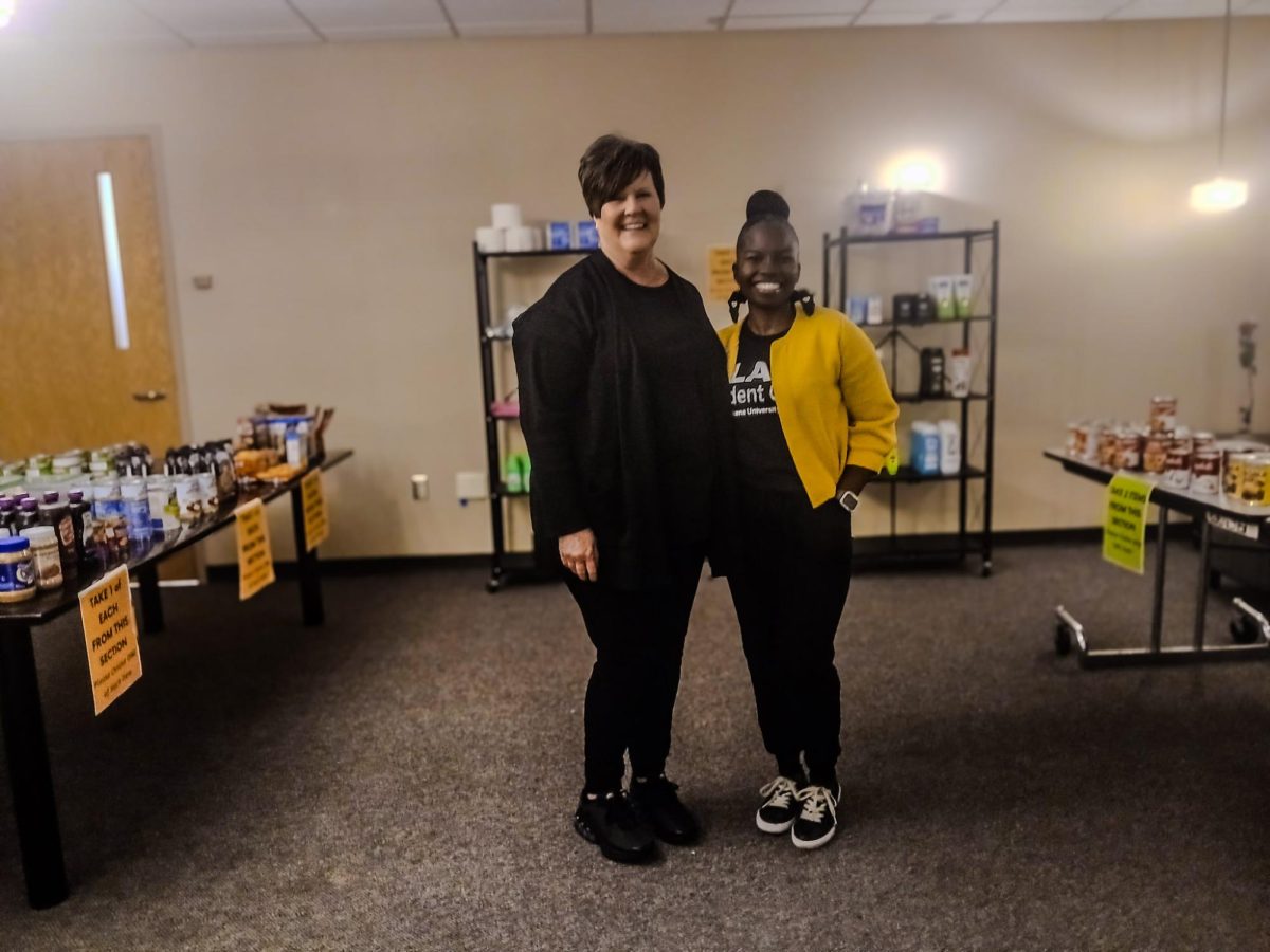 bbie Lorenz and Raven Beard stand in front of tables with food, hygiene products and more.